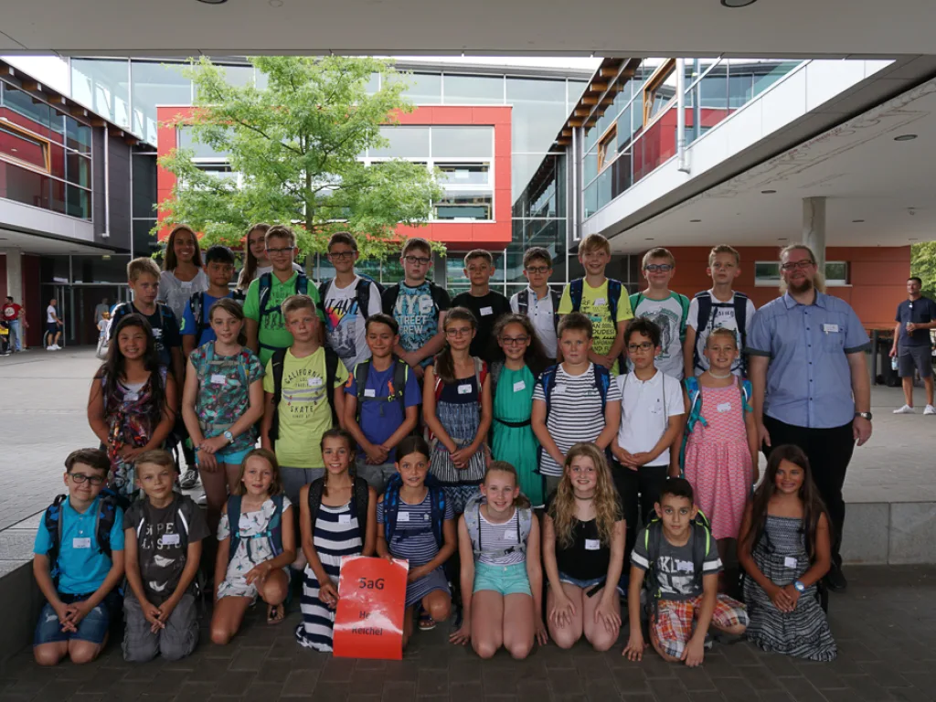 Klassenfoto einer neuen fünften Klasse vor der roten Wand.